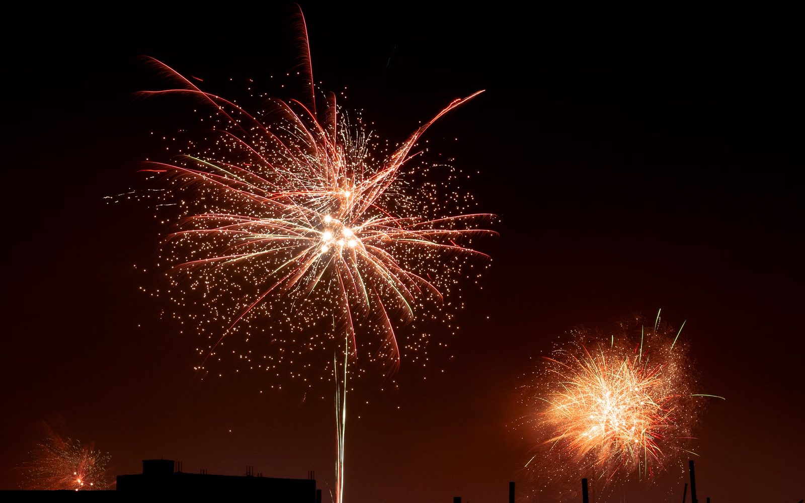 Buntes Feuerwerk über den Dächern einer Stadt in der Silvesternacht