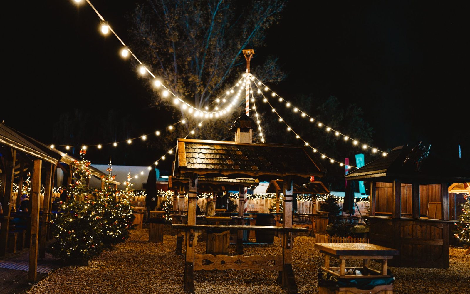 Weihnachtsmarkt bei Nacht unter Lichterketten
